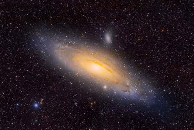 A yellow and blue-colored galaxy shown amongst space and stars. 