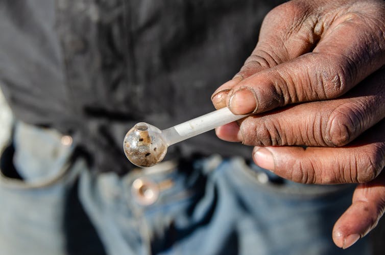 Photo d’une personne tenant une pipe en verre.