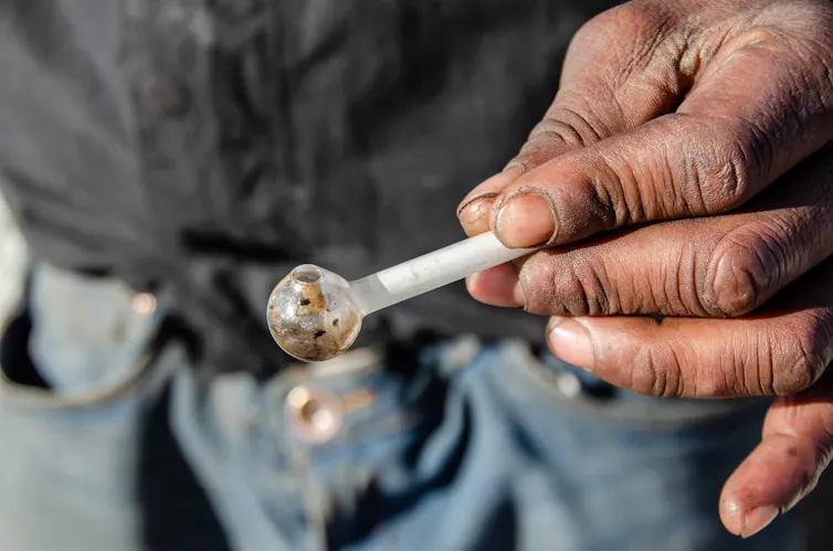 Photo d’une personne tenant une pipe en verre.