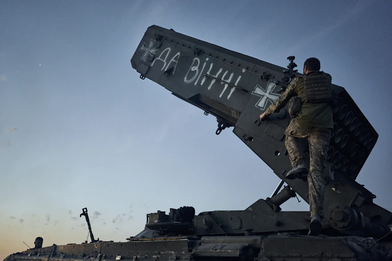 A soldier stands at the base of a rocket launcher.