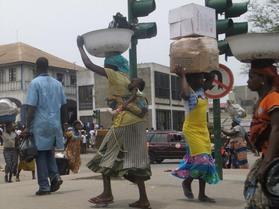 Mena nd women carrying loads on their heads walking in the street