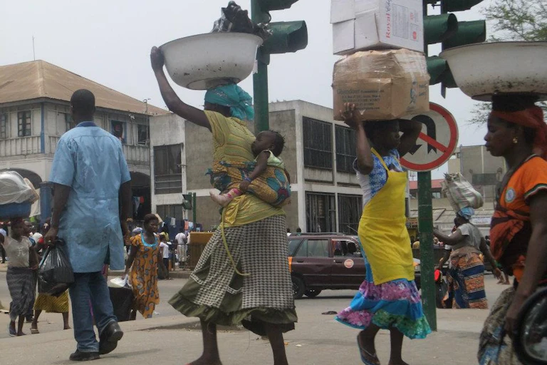 Mena nd women carrying loads on their heads walking in the street
