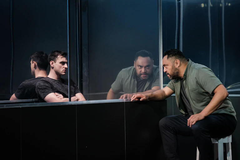 Two actors, divided by a glass screen