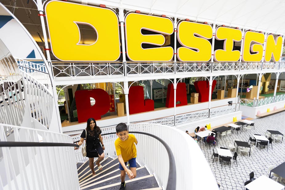 A child runs up stairs in front of the word "design" in large yellow lettering. 