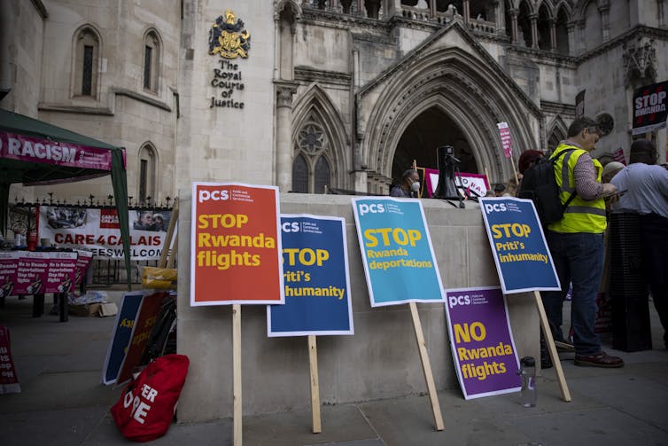 Colourful protest signs opposing the Rwanda deportation flights resting on the ground in front of the Royal Courts of Justice in London.