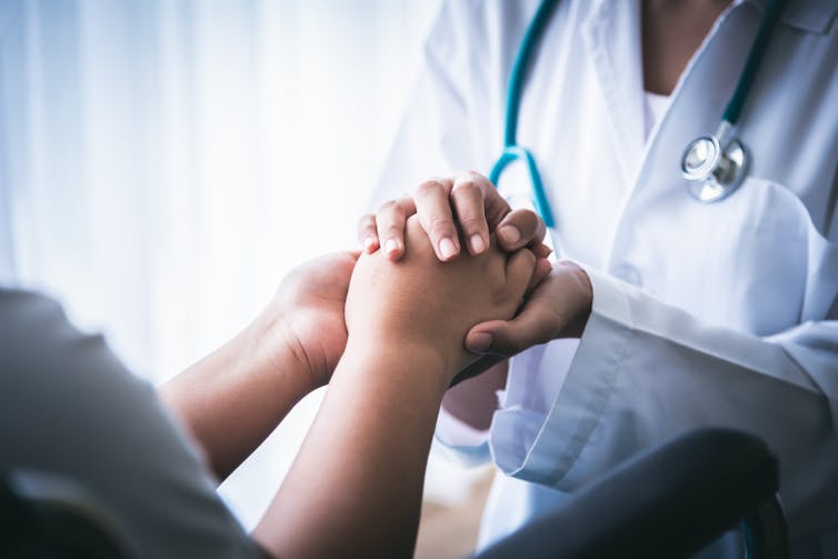 Médico cogiendo la mano de su paciente.