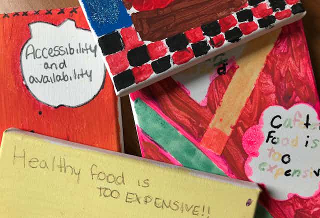 Schoolchildren's artwork on canvas. One says 'healthy food is too expensive'