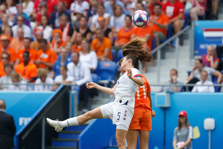 Two women footballers go up to head the ball