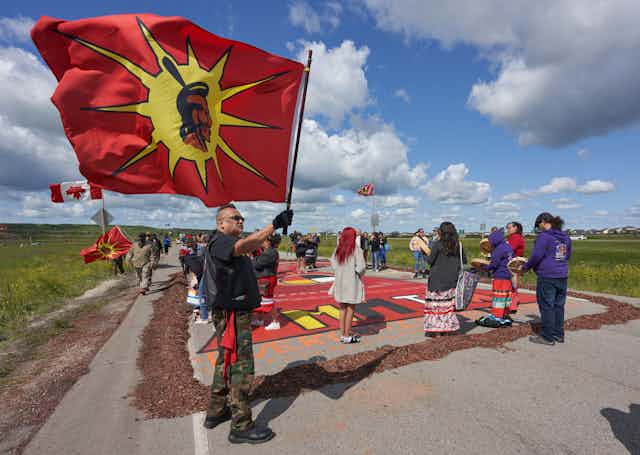 People stand on a highway waving flags.