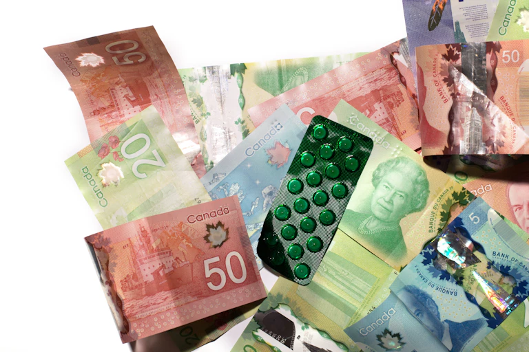 stock photo of Canadian currency with a pack of the pills in green plastic packaging