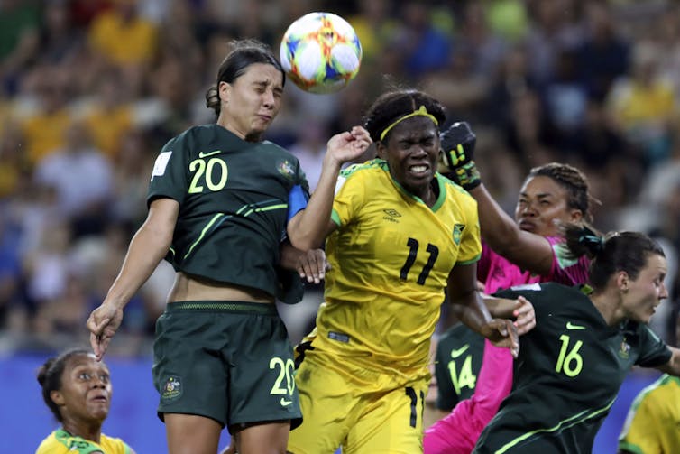 Two soccer players jump to try and head a soccer ball