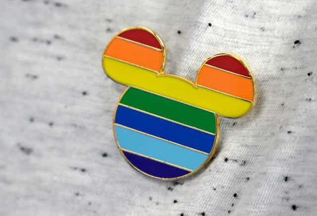 a mickey mouse pin with rainbow colors adorns a worker's shirt