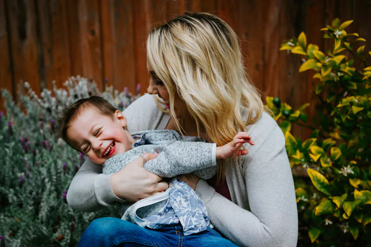 woman holds young child, both laughing