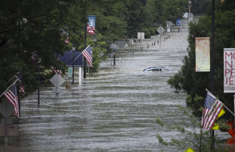 flooded street with US flags and submerged car