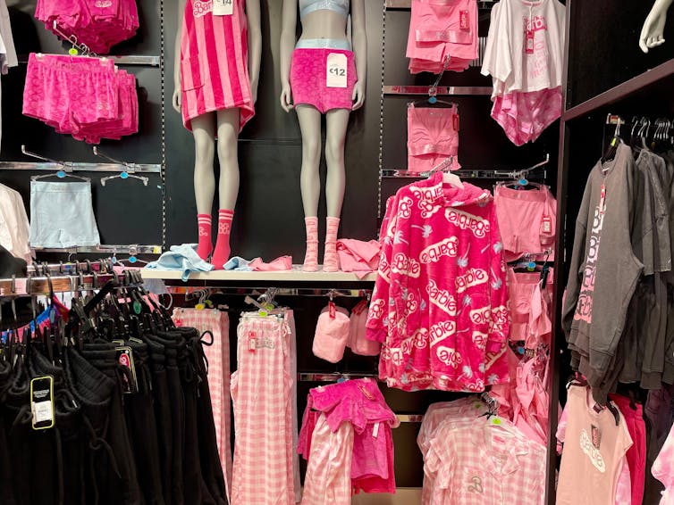 Hot pink dresses, shirts and other Barbie-inspired clothing on display in a shop.