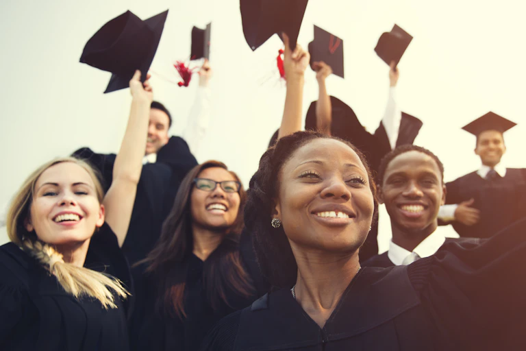 Graduating students throw mortarboards in the air
