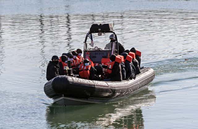 A small border force boat carrying migrants in life jackets