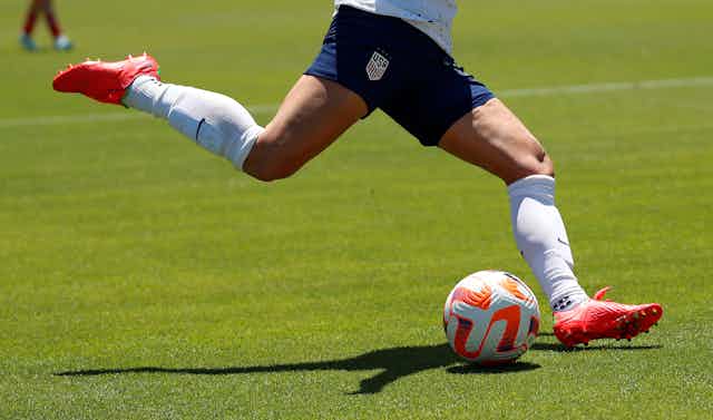 A soccer player about to kick a soccer ball on a field