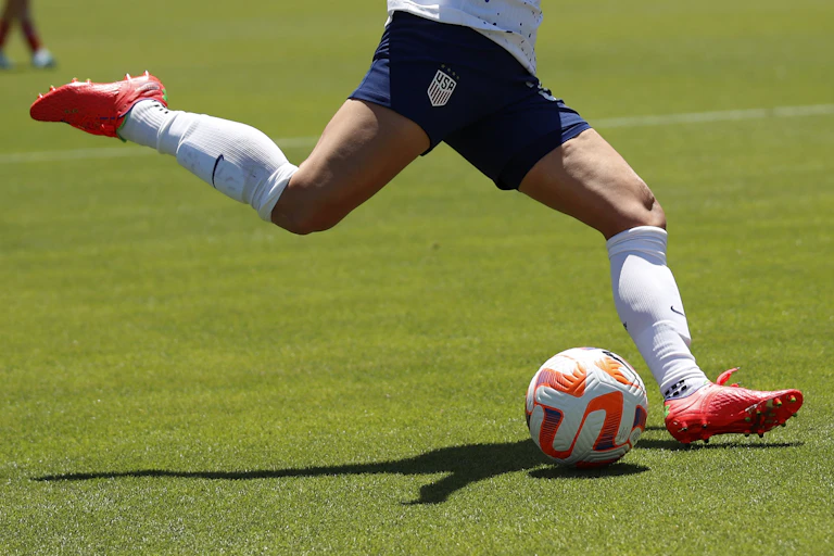 A soccer player about to kick a soccer ball on a field
