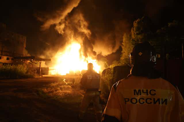 Firefighters look at a huge night-time blaze.
