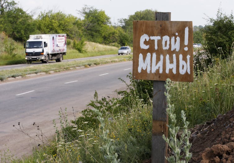 A roadside sign says Stop! Mines! in Ukrainian
