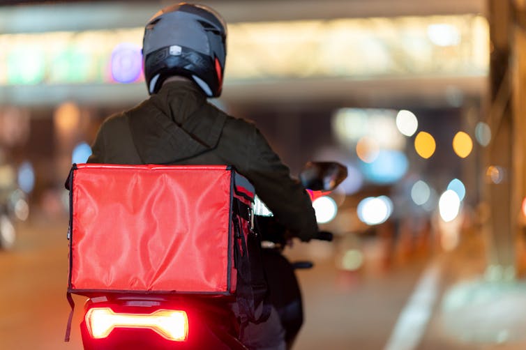 Pizza delivery person driving motor scooter