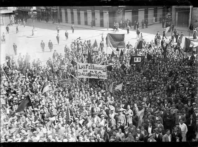 Black and white photograph of a crowd with banners and Spanish Republican flags,