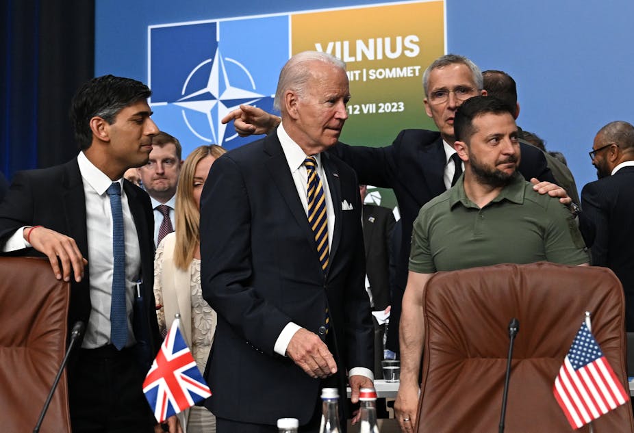 Rishi Sunak, Joe Biden, Jens Stoltenberg et Volodymyr Zenesky devant un panneau de l'OTAN