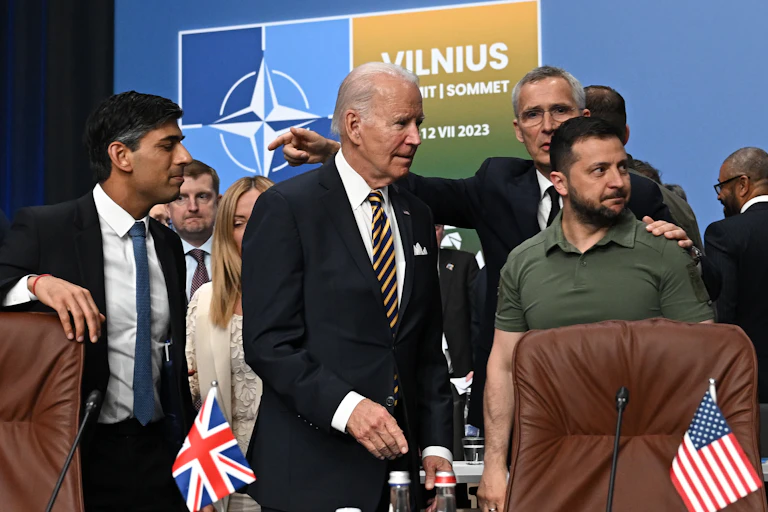 Rishi Sunak, Joe Biden, Jens Stoltenberg et Volodymyr Zenesky devant un panneau de l'OTAN