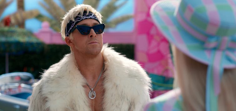 Ken wears a white fur jacket, bandana and dark sunglasses.