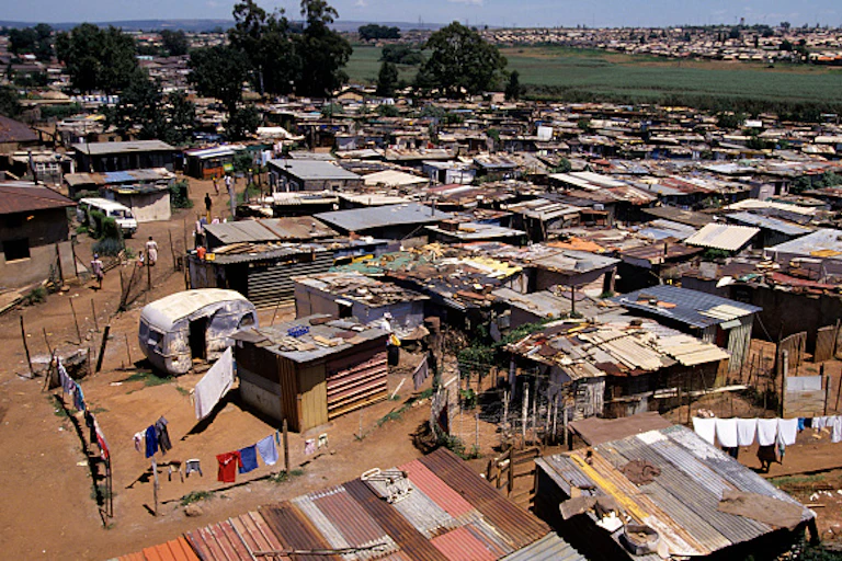 Aerial view of crowded settlement of small structures, with unpaved spaces between them