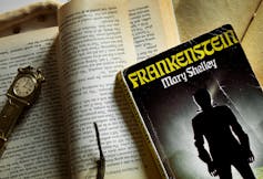 Frankenstein novel seen with a clock and against printed pages.