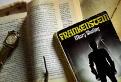 Frankenstein novel seen with a clock and against printed pages.