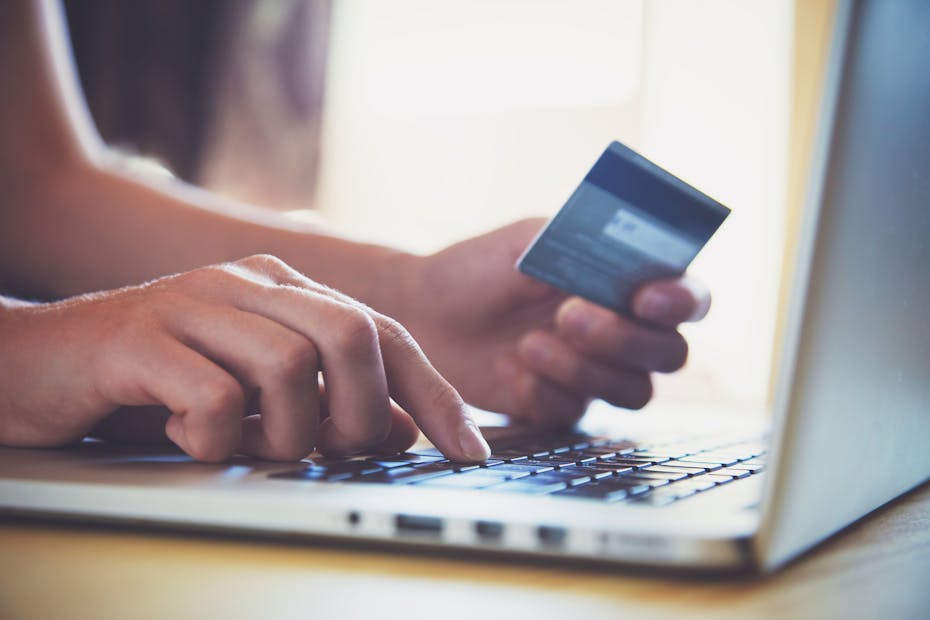 A person inputting payment card details into a laptop.