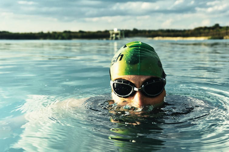 Man wearing diving goggles with his head out of the water.