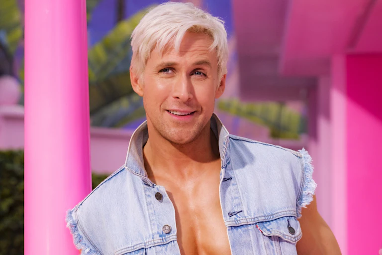 Ryan Gosling with bleach blonde hair wearing an open denim gilet.