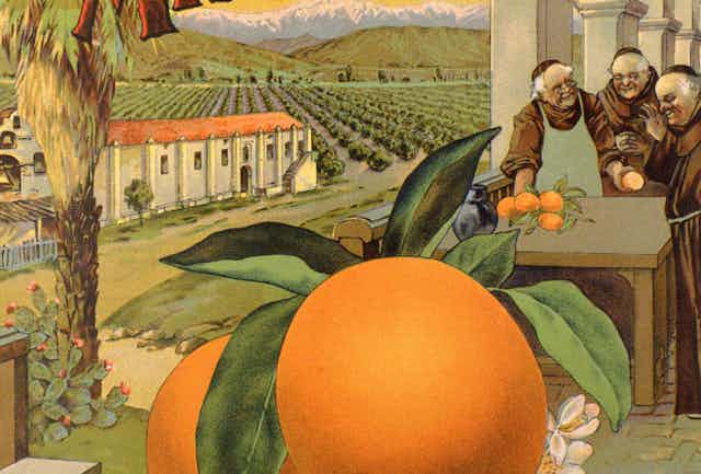 Three monks stand around a table with oranges outside a building with Spanish columns and a large orange grove in the background and snow-capped mountains beyond.