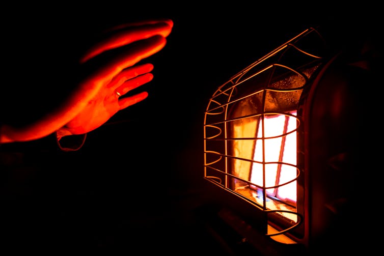 hands reach towards gas heater