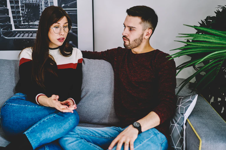 A woman and a man on a couch talking.