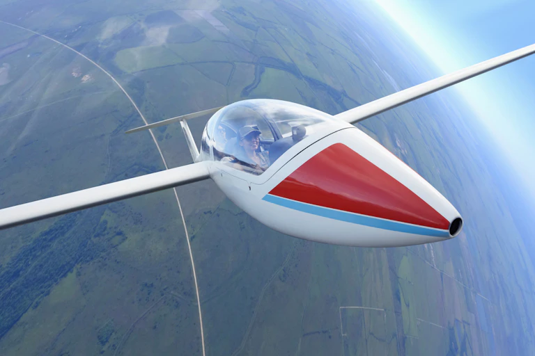 a glider piloted by a woman soars high above a landscape of farm fields
