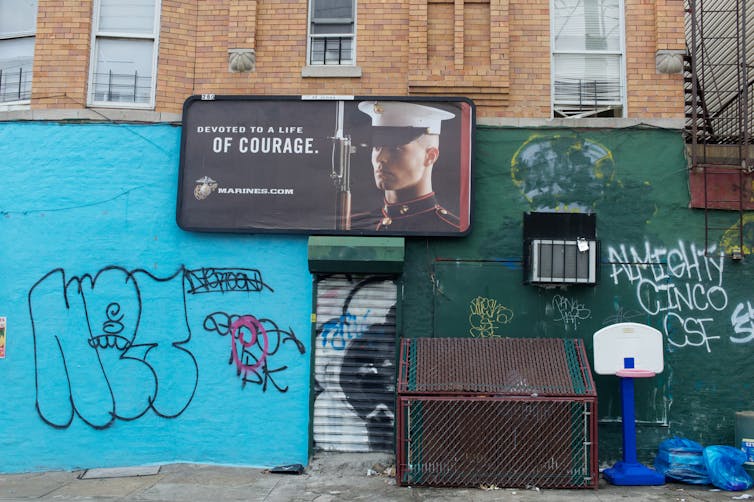 A poster of a man in a military uniform is on a wall with different types of graffiti.