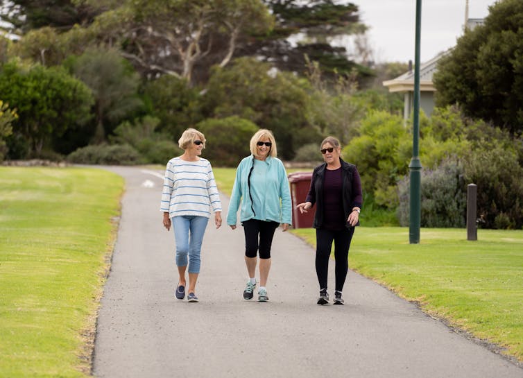 three women walking along outdoor path together
