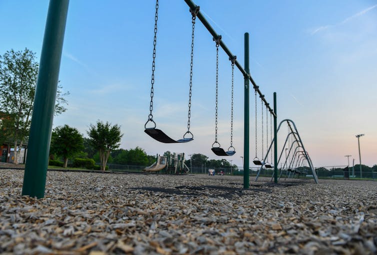 A row of swings on a playground, seen from above as dusk starts to fall.