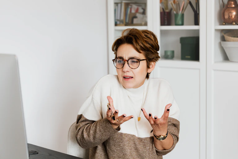 A woman speaks at a computer screen, using hand gestures.