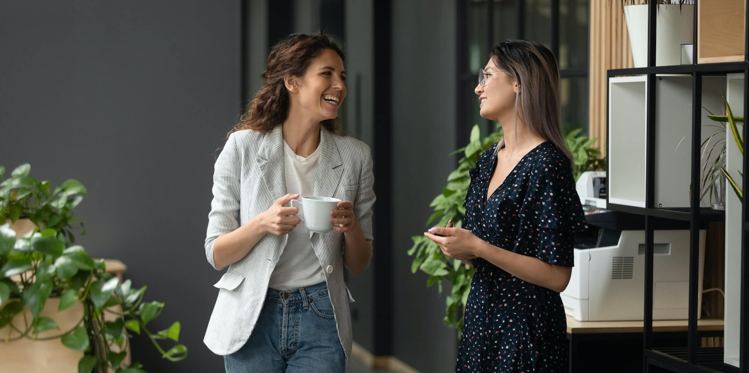 Deux femmes en tenue de travail discutent dans un bureau. en prenant un café