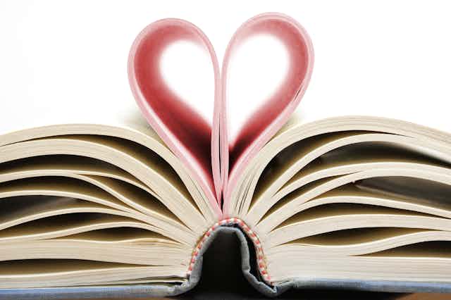 Un libro abierto con las páginas centrales dobladas formando un corazón.
