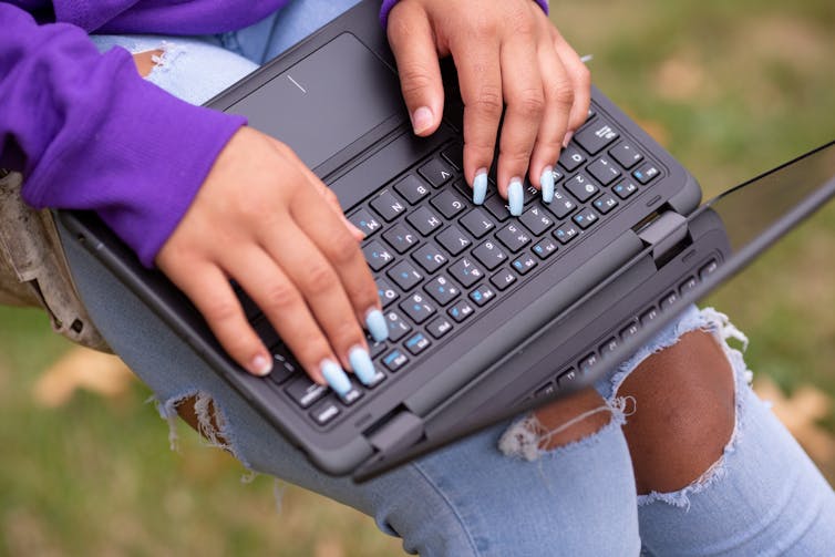 A teen's hands seen on a laptop.
