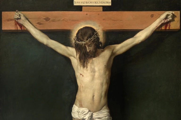 Un hombre medio desnudo cuelga, crucificado, de una cruz de madera.