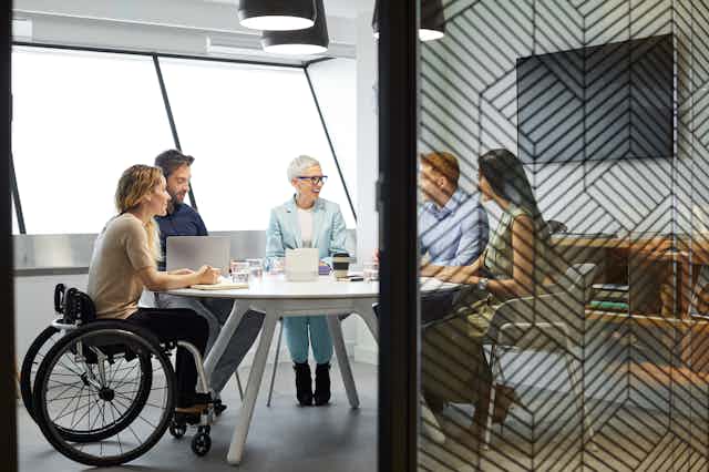 group of people around office table, one in wheelchair