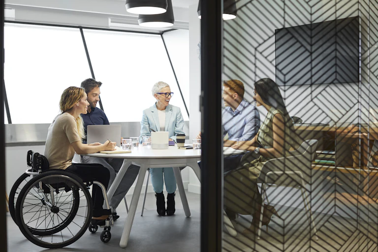 group of people around office table, one in wheelchair